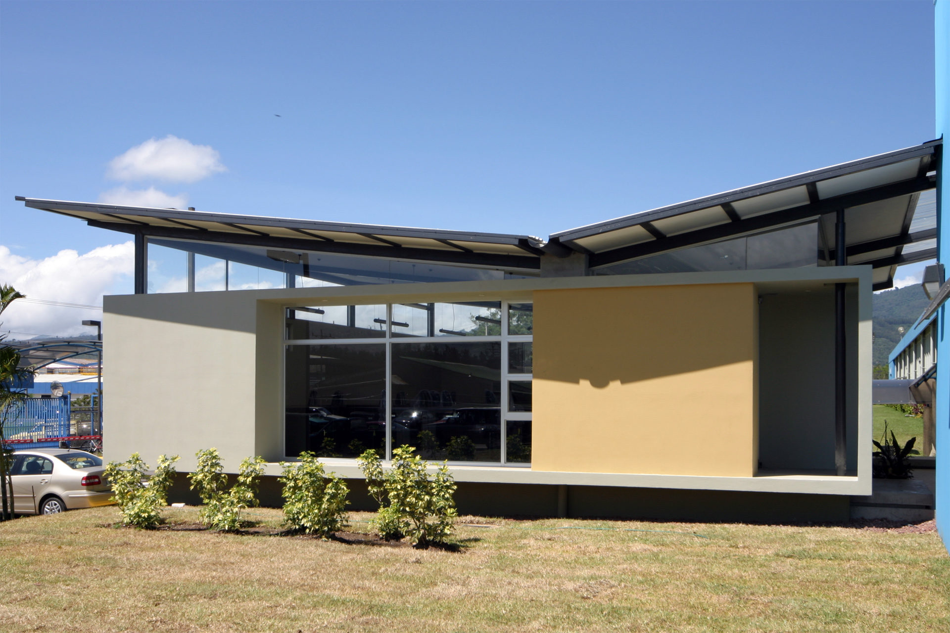 Frontal view of the Novartis Software Development Office, highlighting the unique inverted-pitched roofs with a round scupper drain. Quality Costa Rican Contemporary Design