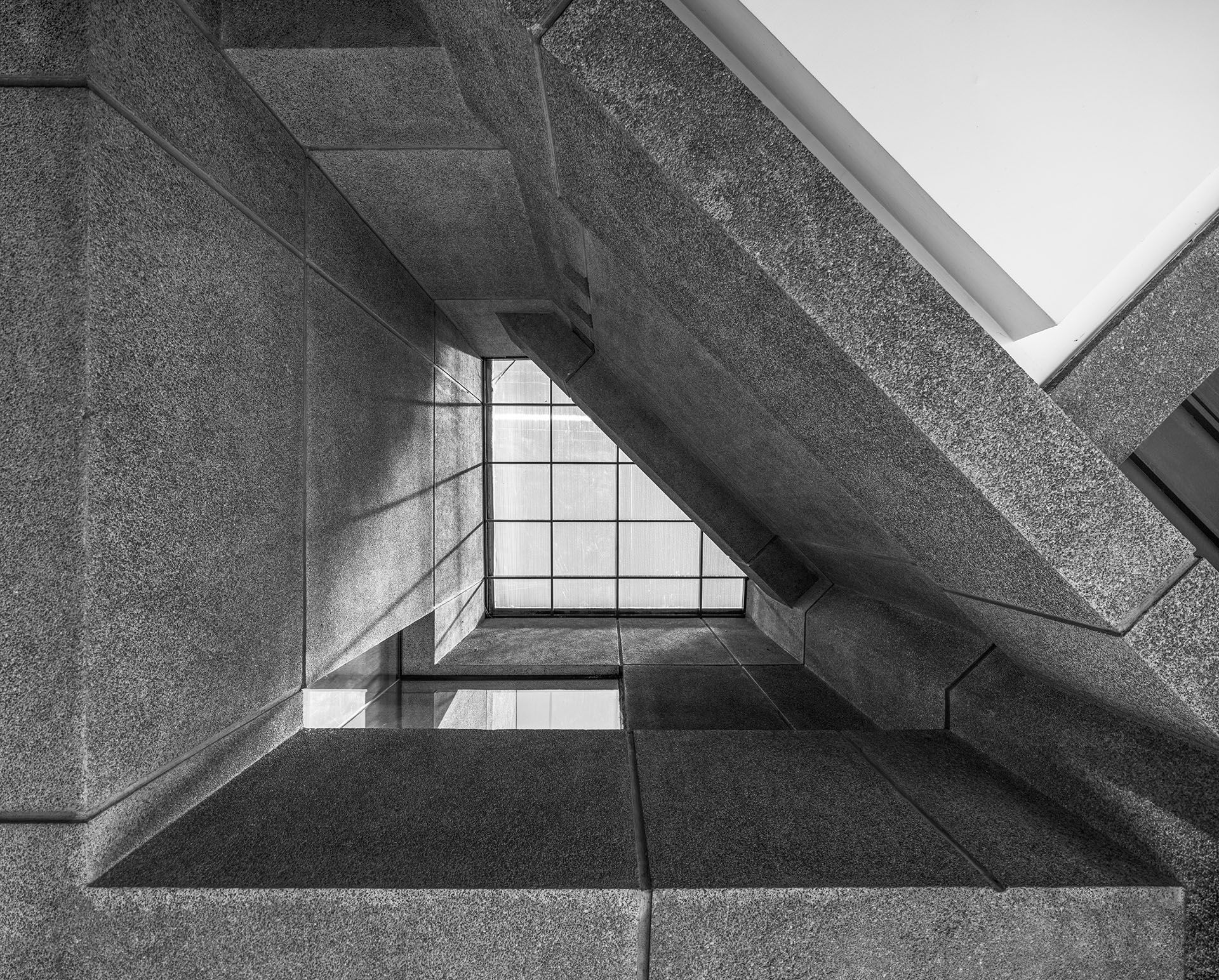 Black and white detail photo of a translucent atrium in Plaza Rolex, surrounded by solid concrete walls
