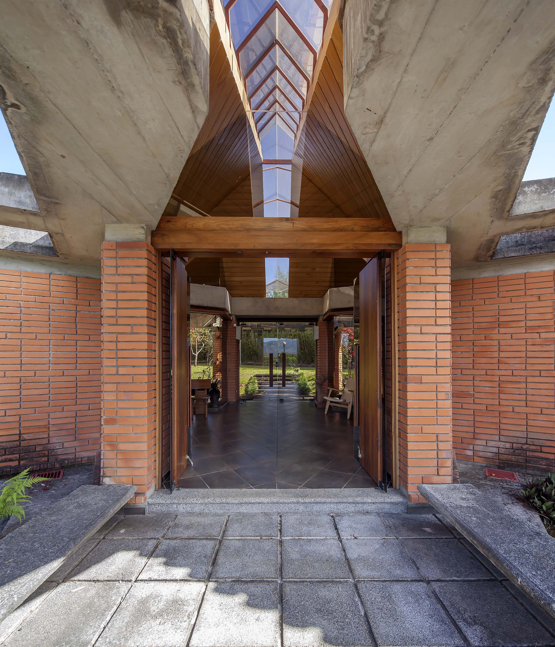 Close-up view of Soto House's main entrance, showcasing open doors leading into the lobby. Visible details include concrete walls, cantilevered concrete beams, and an axial skylight.