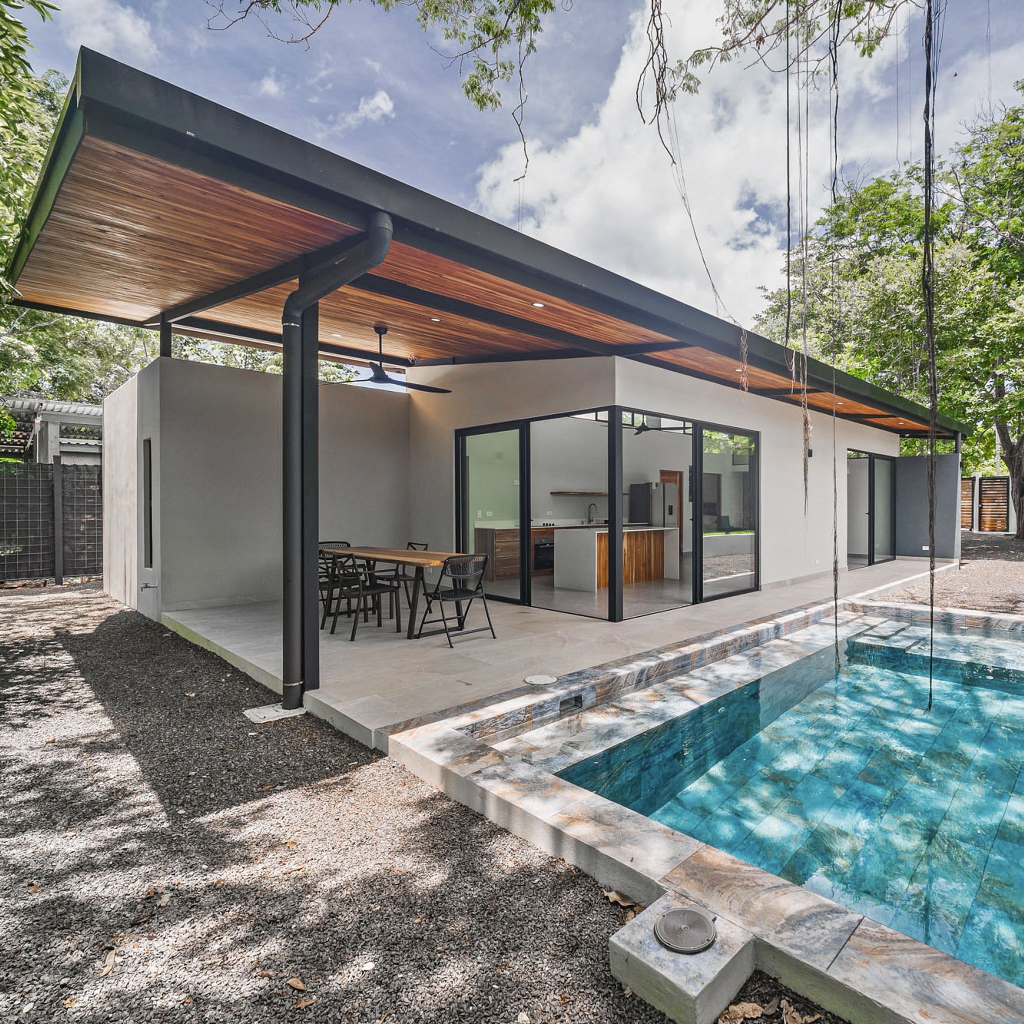 View from the terrace showing the pool and the full social façade beneath the floating roof.